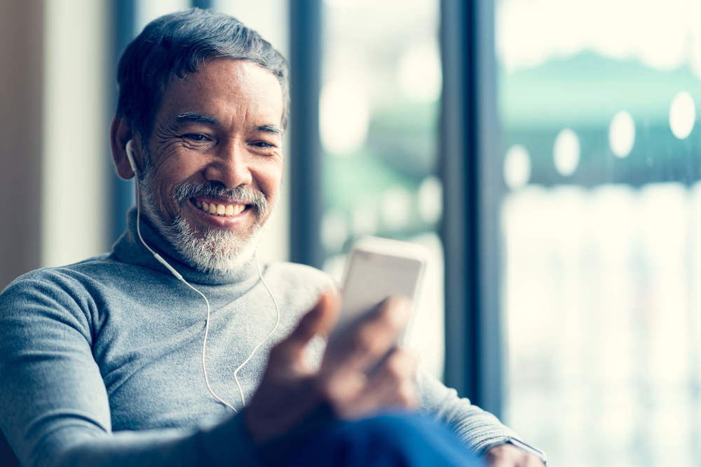 Man with headphones in looking at phone smiling