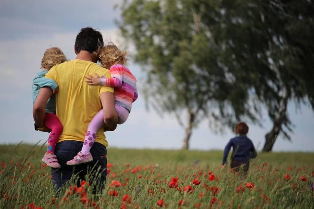 Man holding children in poppy field