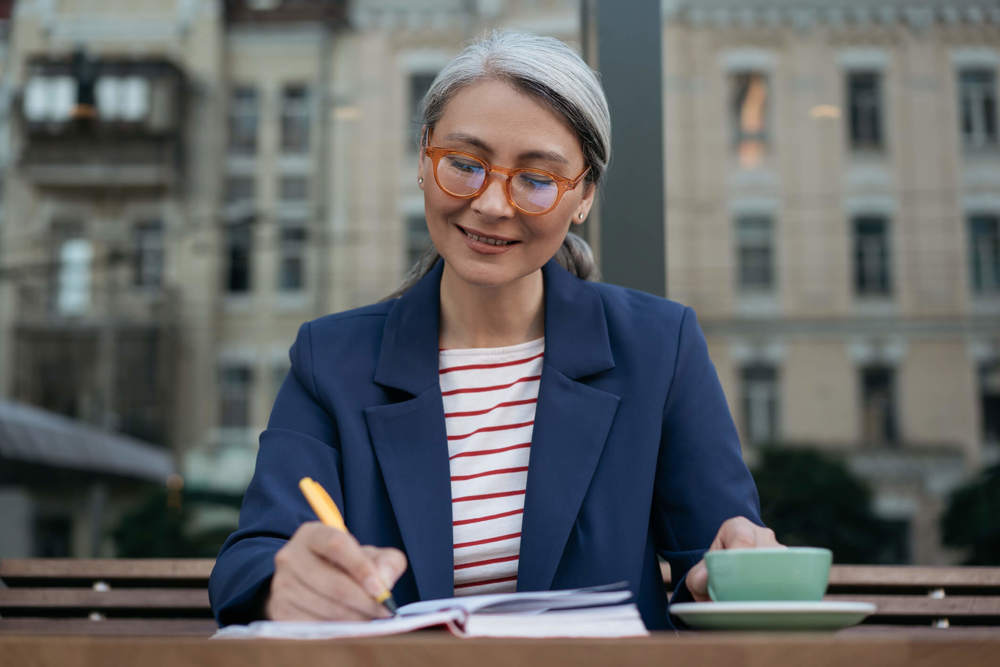 Woman sat at desk writing on paper smiling