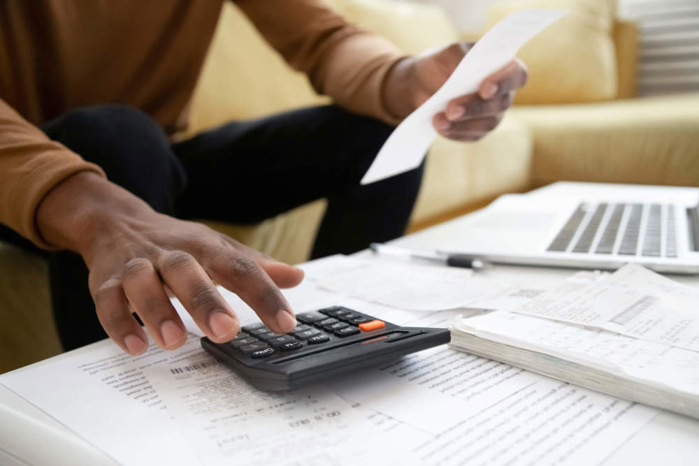 Man holding paper while touching calculator