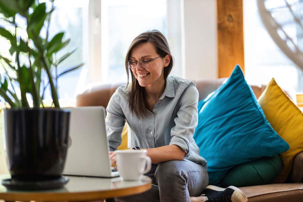 Woman sat at coffee table on laptop smiling